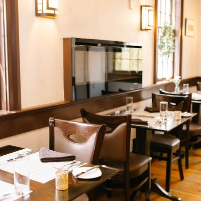 Tables set with glasses, napkins, and silverware, a wall mounted electric fireplace.