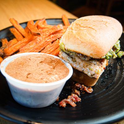 Grilled salmon sandwich with sweet potato fries and dipping sauce.
