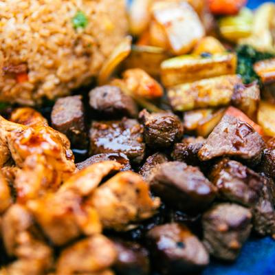 Grilled meat with fried rice and sauteed vegetables.