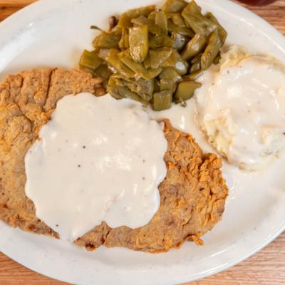 Chicken Fried Steak served with mashed potatoes and gravy and green beans.