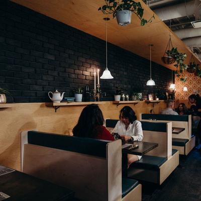 Guests seated at booths under soft lights and hanging plants.