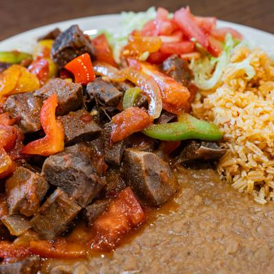 Mexican beef plate with peppers, tomatoes, refried beans, and rice.