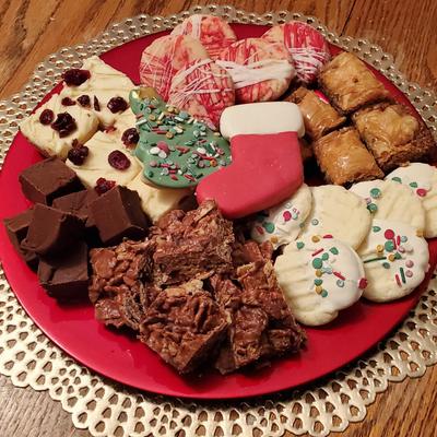 A red plate on a wooden table holds assorted holiday cookies.
