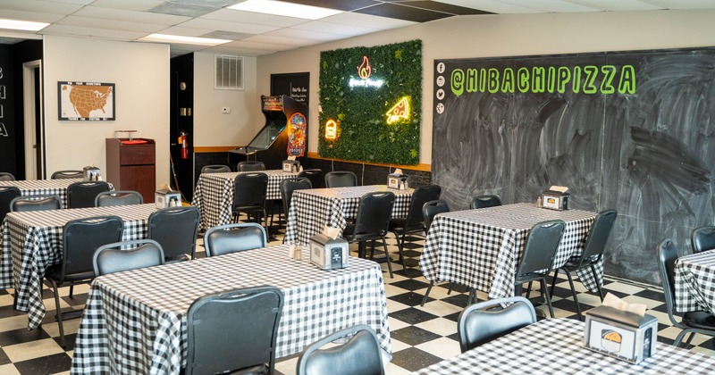 Interior, dining area, tables for four, checkered black and white tile flooring, menu board