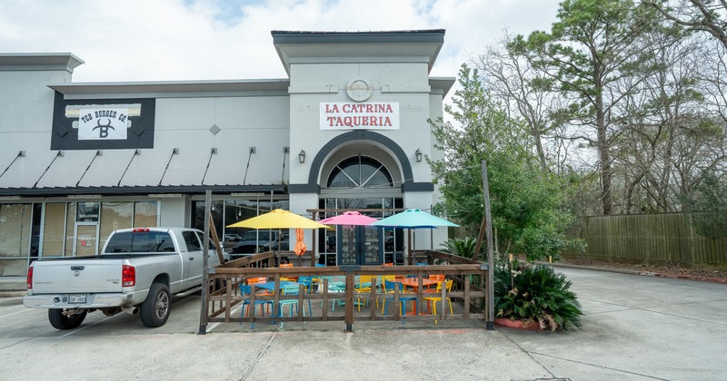 Exterior, front view to restaurant, patio, tables, chairs, parasols in front of entrance, sign above