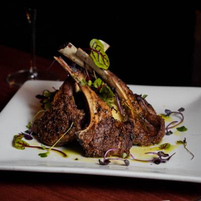 Dish of seasoned grilled lamb chops garnished with microgreens.