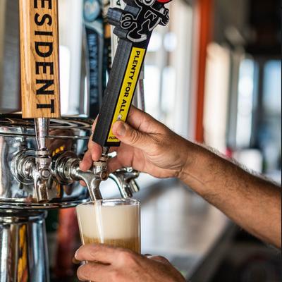 A hand pouring beer from the dispensary.