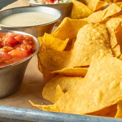 Tortilla chips with salsa and sour cream, close up.