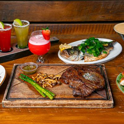 Beef ribeye steak and grilled branzino with cocktails.
