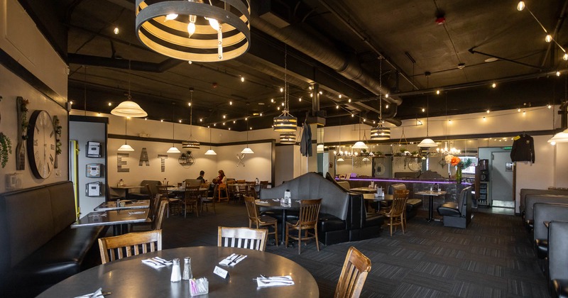 Modern restaurant interior with round tables, booth seating, and pendant lights