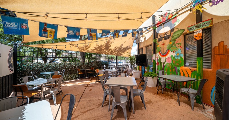 Outdoor seating area at a café, shaded by a beige canopy