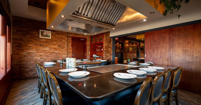 Interior view of a teppanyaki restaurant with a large U-shaped granite table and chairs