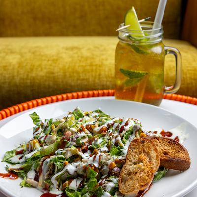 Plated salad with toast on the side, alongside a drink garnished with lime wedges.