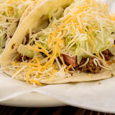 Gringo style taco topped with shredded lettuce and cheese.