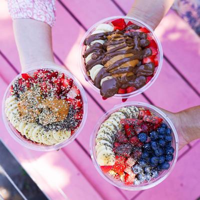 Multiple acai bowls served on table outside.