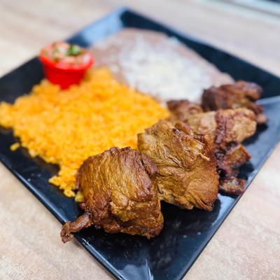 Grilled meat chunks served with rice and refried beans.