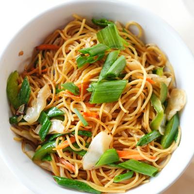 Veggie noodles topped with chopped green onion, overhead view.