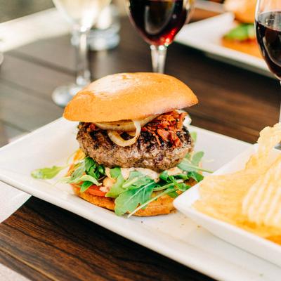 Wagyu Beef Burger, with cheese, sauteed onions, baby arugula, tomatoes, bacon, and pickles.
