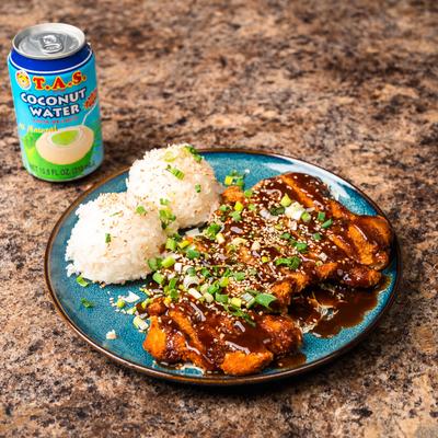 Pork Katsu plate served on a marbled table with a can of coconut water.