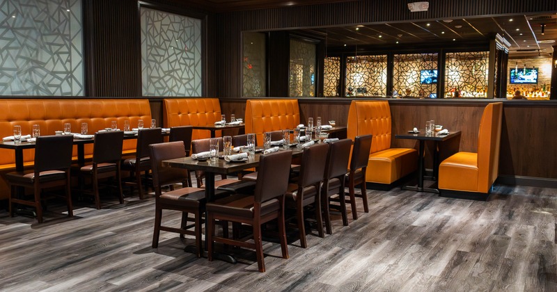 Modern interior with brown wooden chairs and orange booths, geometric partitions and a bar area
