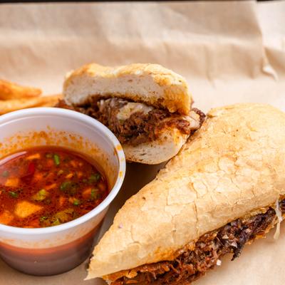 Shredded Beef sandwich served with a side of savory dipping jus, close-up.