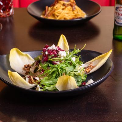 Salad with endives, arugula, radish, walnuts, goat cheese, balsamic, honey, and olive oil.