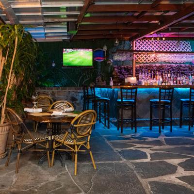 Outdoor seating area featuring tables and chairs arranged in front of a bar.