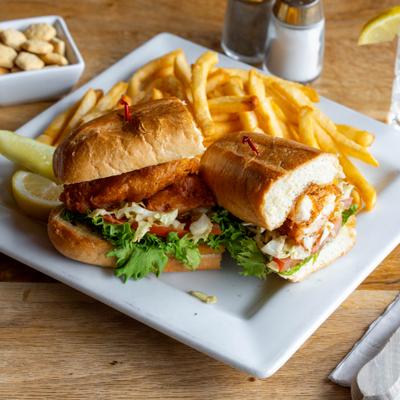 Halibut Po'boy sandwich served with fries, pickel and a lemon wedge.