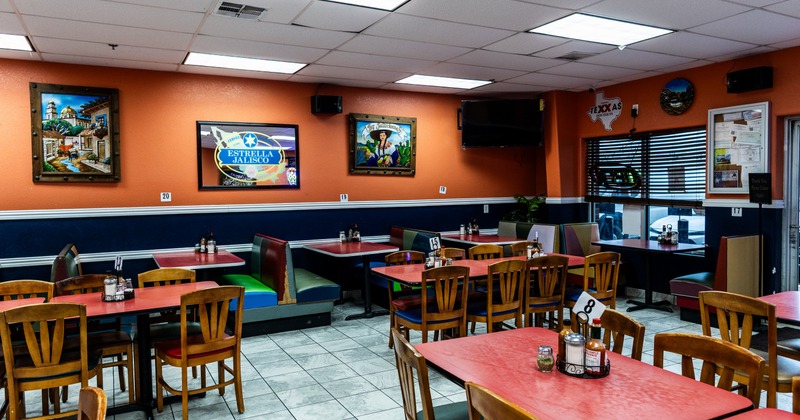 Interior of a restaurant wit orange walls and red wooden tables