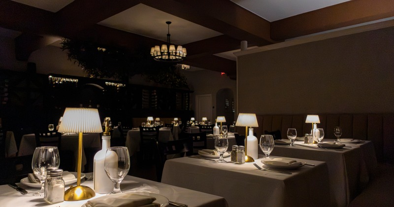 Elegant dining room with round tables, white tablecloths, and chandelier lighting