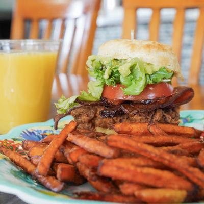 Fried chicken biscuit sandwich with bacon, tomato, lettuce, and sweet potato fries.