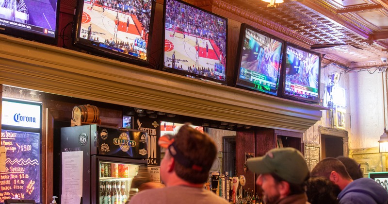 Interior, guests at the bar watching basketball TV broadcast