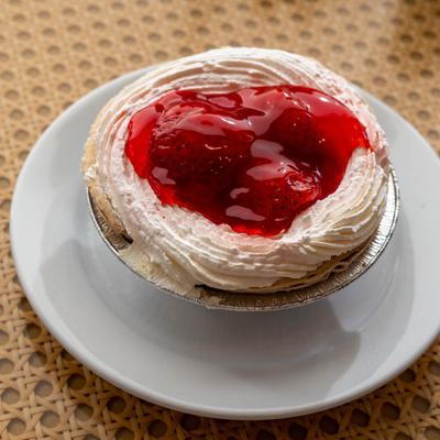 Strawberry pie with whipped cream and glazed strawberries in a foil tin.