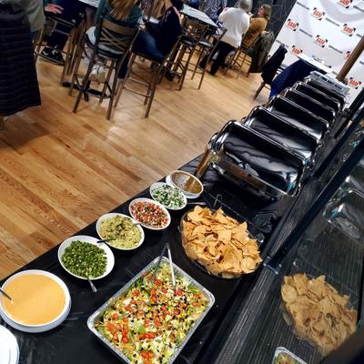 Catering table set up with various appetizers and warm food in chafing dishes.