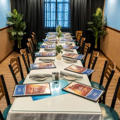 Interior, a long dining table with wooden chairs is set for an event, featuring menus and napkins.