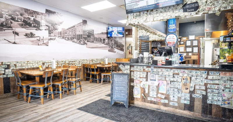 Interior, rustic design, seating area and order counter, walls covered in dollar bills