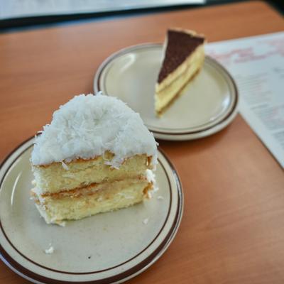 Slices of coconut cake and tiramisu cake on plates.
