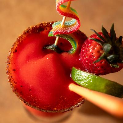 Strawberry Daquiri garnished with citrus slices, fresh strawberry and sour candy belt.