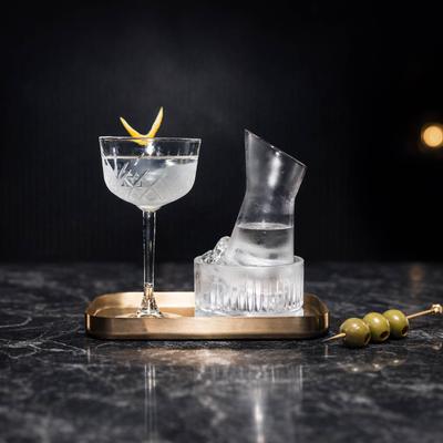 Martini cocktail served in a angled carafe resting on a bed of ice with glass and garnishes.