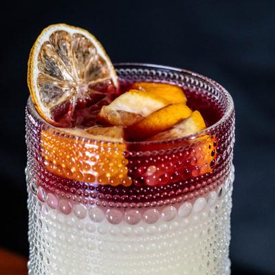 Sangrita cocktail garnished with fresh fruit and dried citrus wheel.