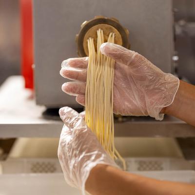 Hands making pasta with the pasta machine.