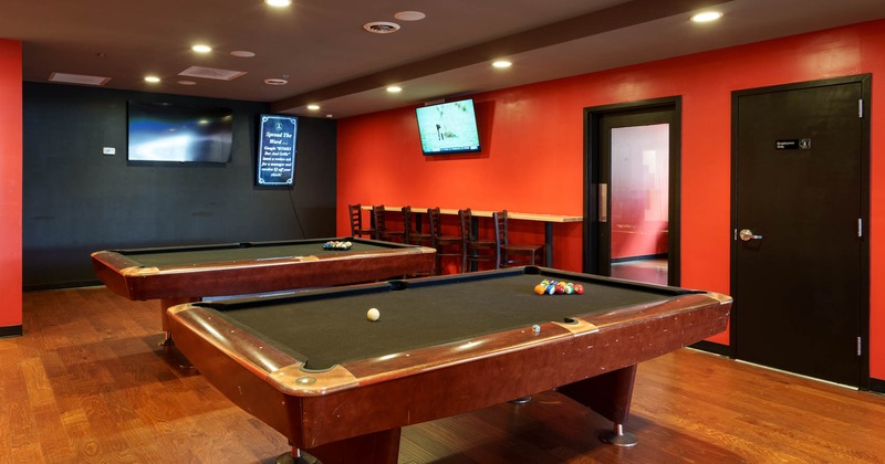 Interior, two pool tables, wall TV screens, wall table with bar chairs