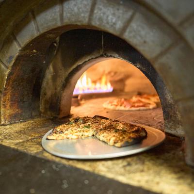 Pizza being cooked inside a traditional brick or stone oven.