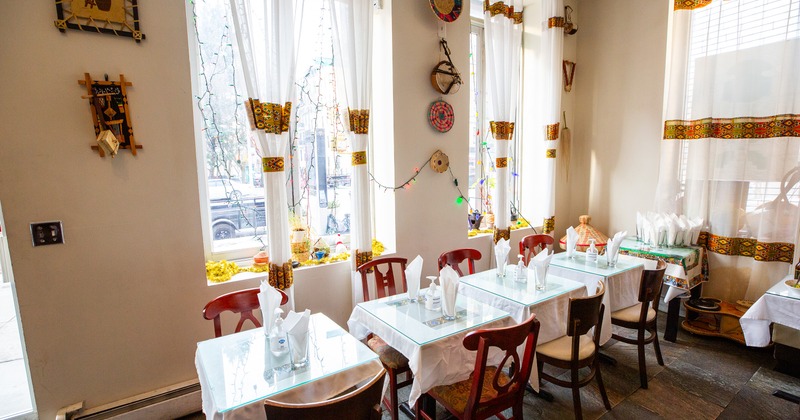Cozy interior space, dining tables set for two guests along the windows