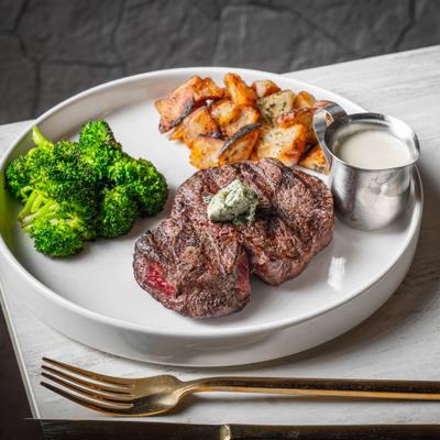 Filet mignon served with broccoli, potatoes, and dressing.