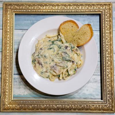 Amici's Alfredo pasta served with bread on the side.