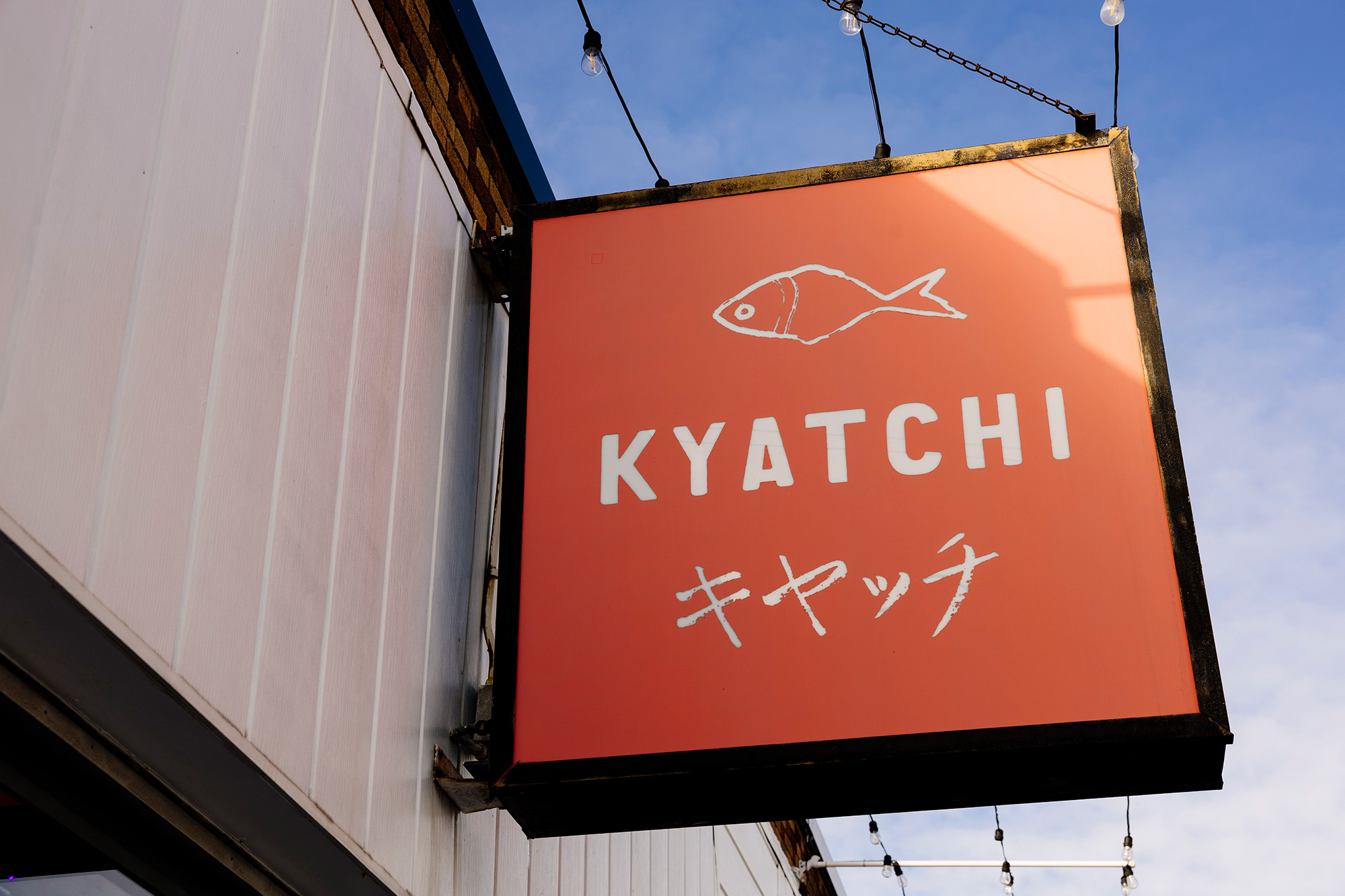Kyatchi restaurant sign with a fish logo on an orange background