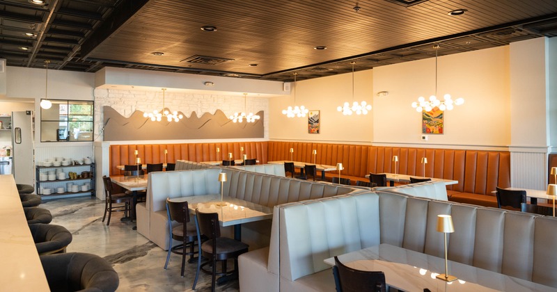 Modern restaurant interior with booths, marble floor, decorative lights, and abstract paintings