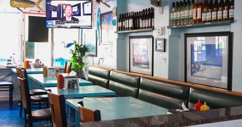 Interior, teal tables and dark green booth seating, wine bottles on a shelf, TV