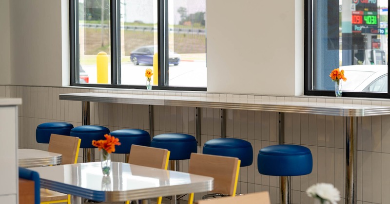 Interior of a café with blue stools, white tables